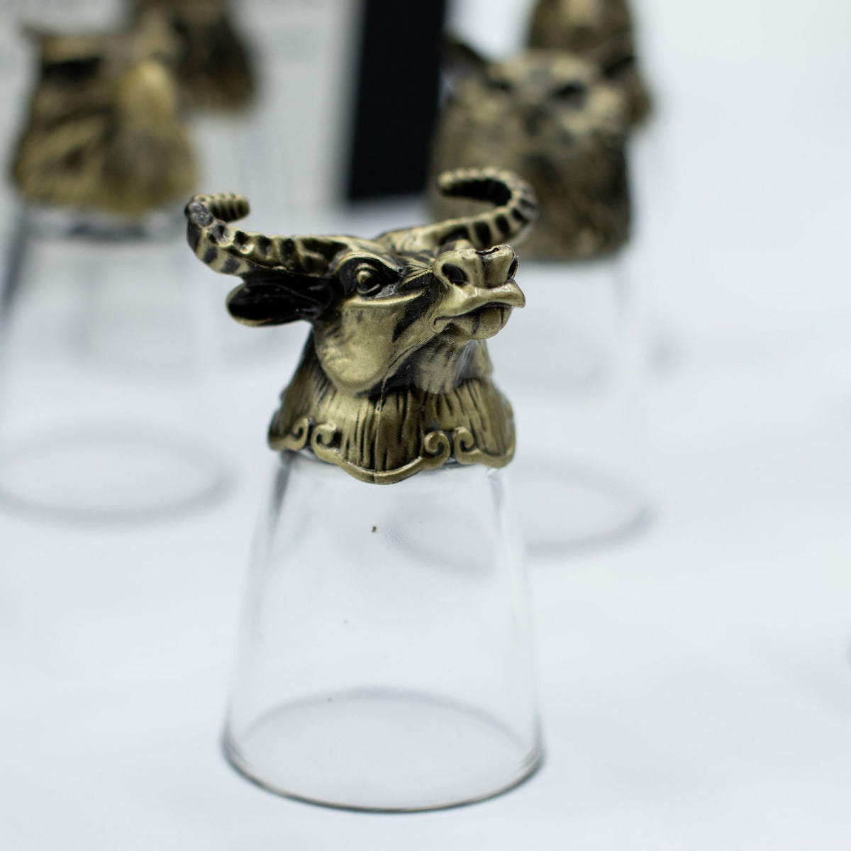 Clear shot glass with antique bronze wild boar creature topper, side view