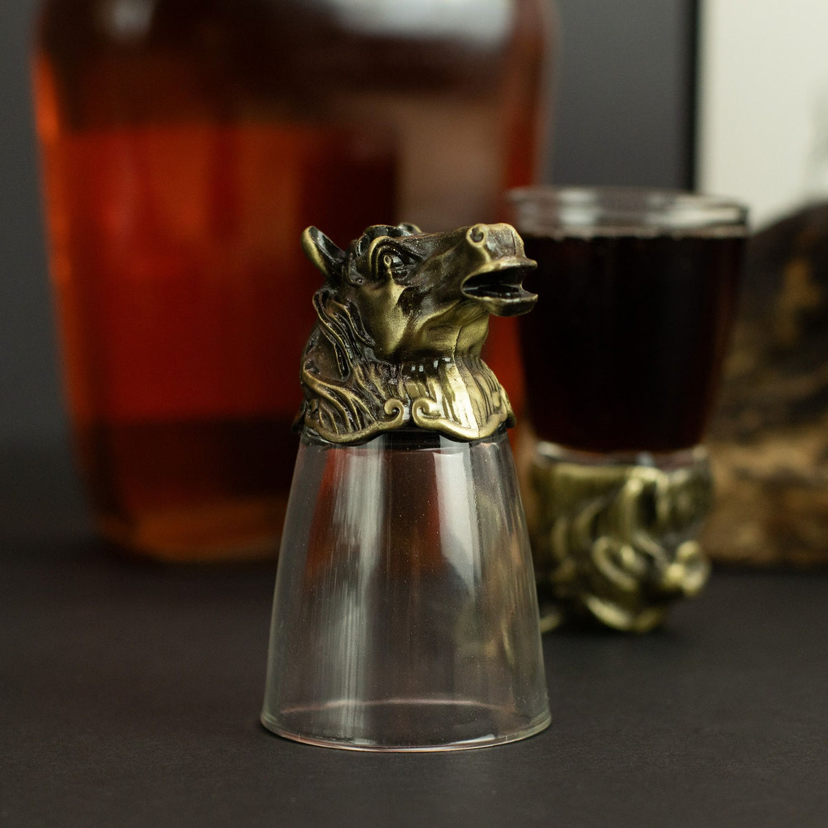 Close-up forest creature shot glass topper in antique bronze on clear glass