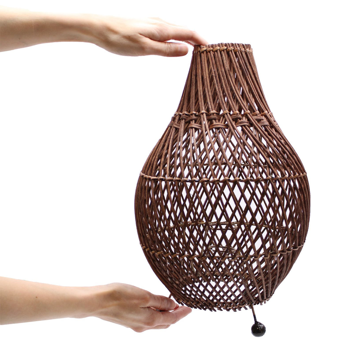 Dark brown rattan table lamp held upright with teardrop woven shade and stand feet