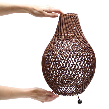 Dark brown rattan table lamp held upright with teardrop woven shade and stand feet