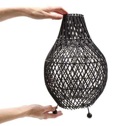 Black rattan teardrop lamp shade held by hands