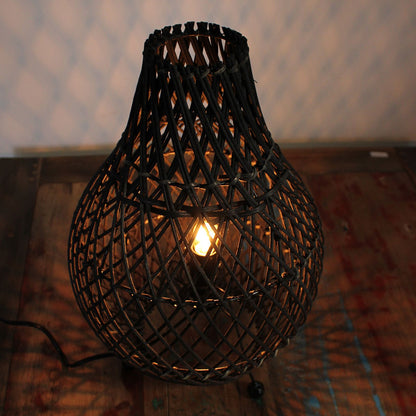 Lit black rattan teardrop table lamp with warm light inside lattice shade