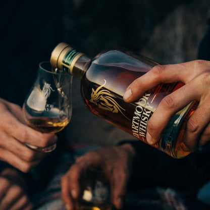 Dartmoor Whisky bottle tilted as it pours, amber liquid and label visible.