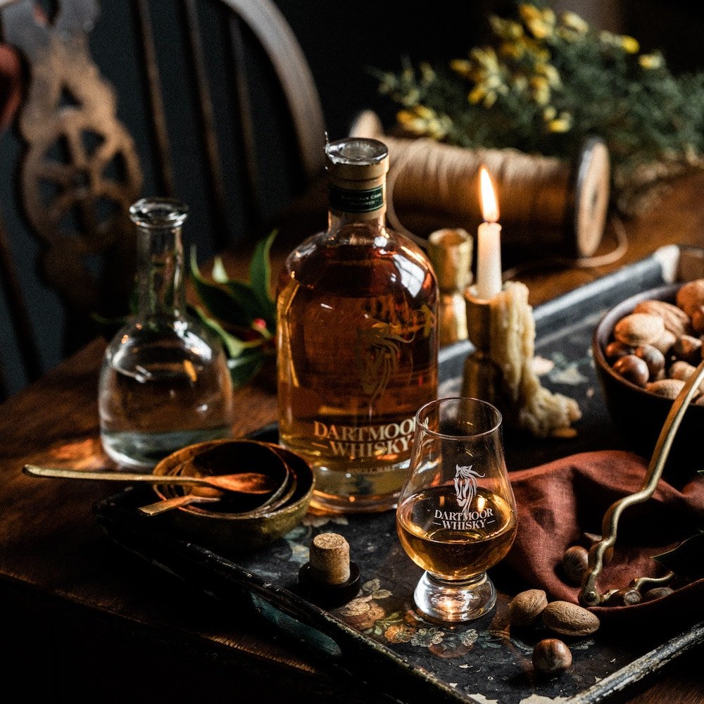 Whisky bottle on a bar tray with a branded snifter glass and candlelight.