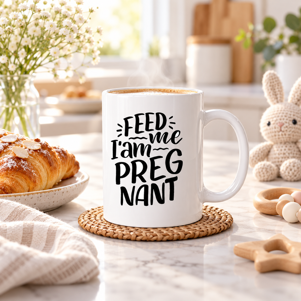 White ceramic mug with black 'FEED ME I AM PREGNANT' text on woven coaster