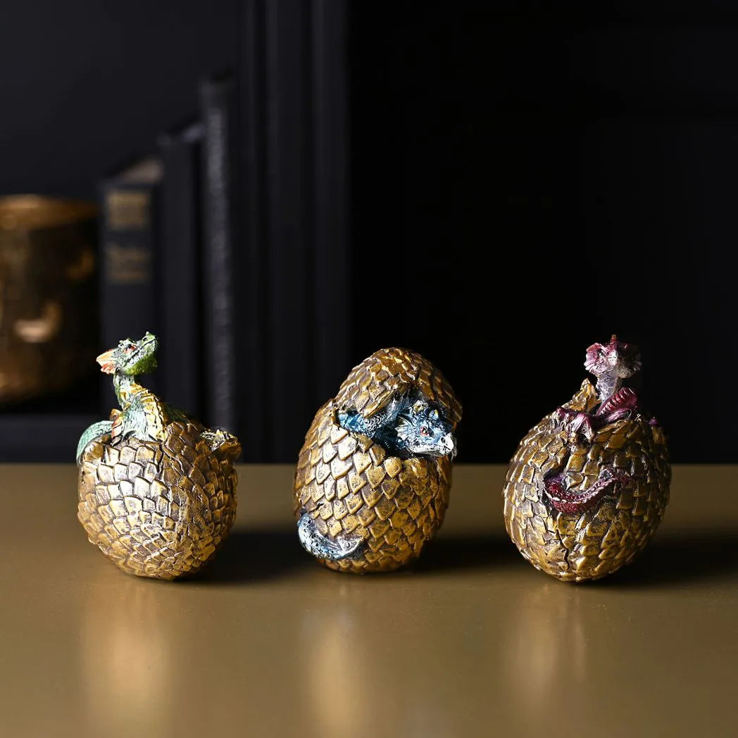 Set of three gold dragon egg figurines with purple and silver hatchlings