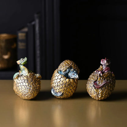 Set of three gold dragon egg figurines with purple and silver hatchlings