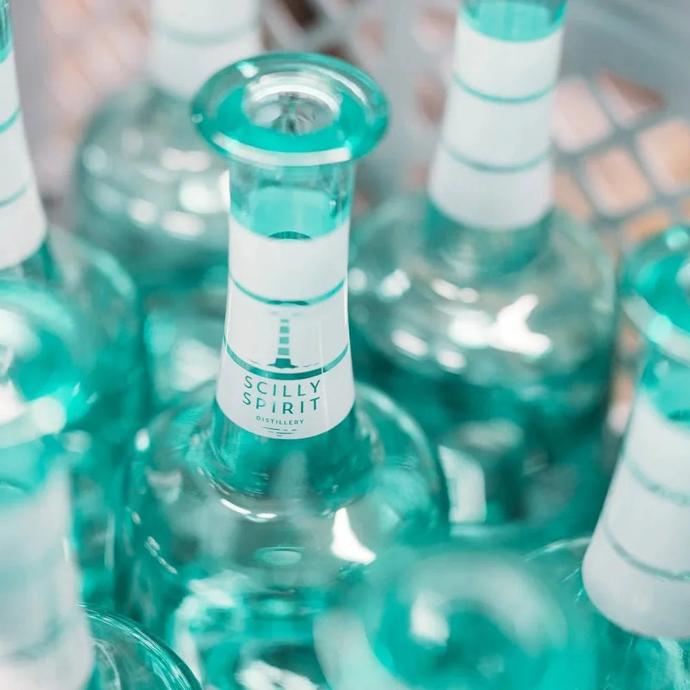 Group of teal glass Island gin bottles with cork tops and “SCILLY SPIRIT” labels