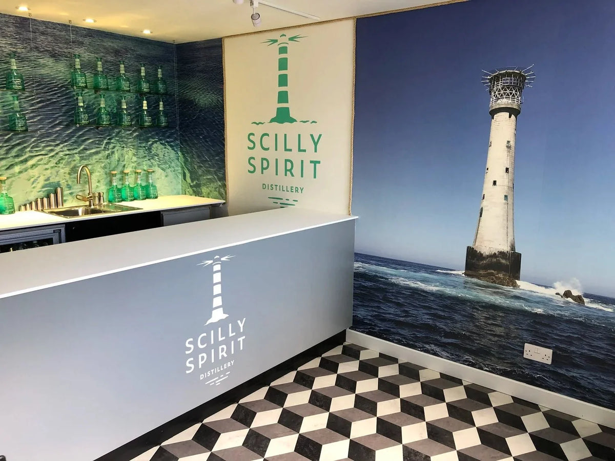 Scilly Spirit branded distillery display wall with bottle graphics and lighthouse photo