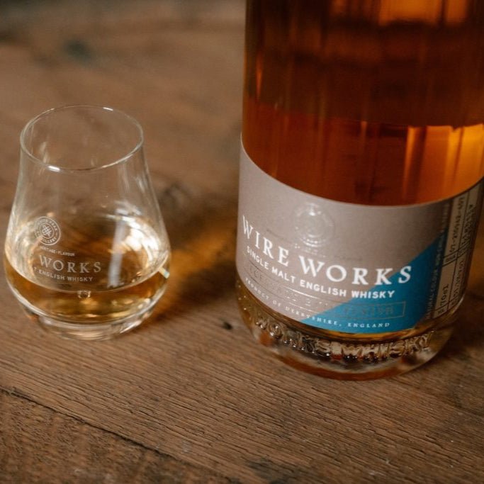 Wire Works whisky bottle base and tumbler glass with amber pour, partial label