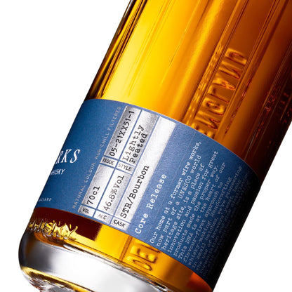 Amber whisky bottle close-up with blue label band and embossed bottle details